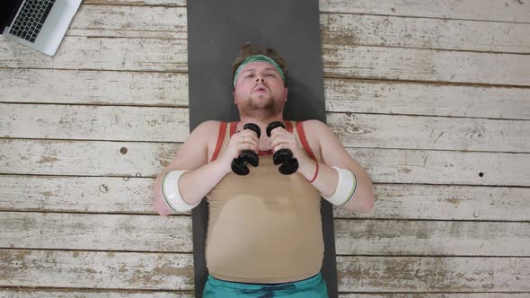 Funny Overweight Sportsman Lying Exhausted Down on the Floor alt