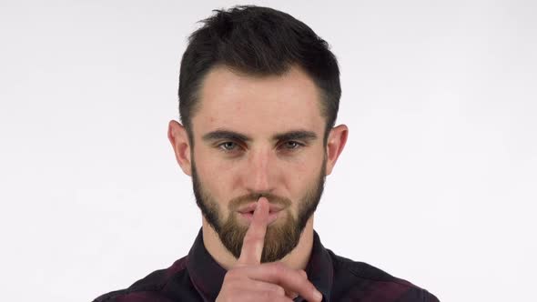 Attractive Bearded Man Shushing To the Camera with Finger To His Lips alt