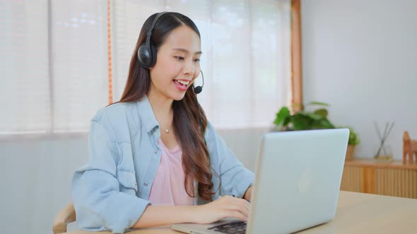 Asian Telemarketing or call center with headset work to support costumer on computer laptop at home. alt