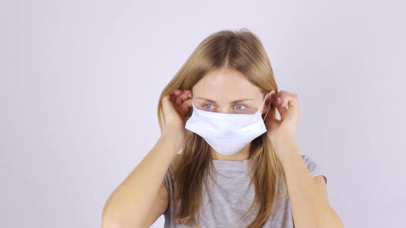 A Woman Puts on a Medical Mask and Looks at the Camera