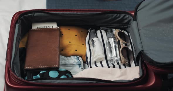 Woman's Hands Packing Suitcase for a Journey on the Bed at Home alt