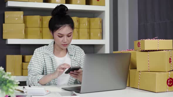 woman working and checking product order with her smartphone at home office
