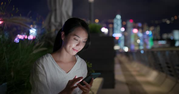 Woman send text message on cellphone at night