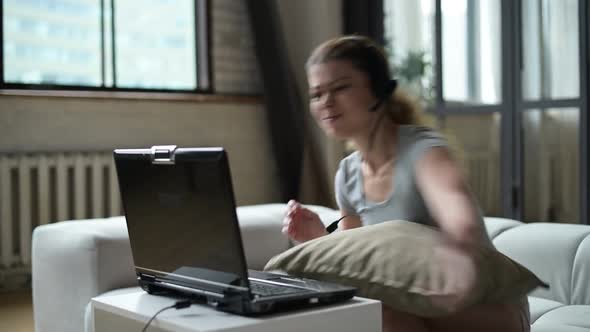 woman gets annoyed and angry at a slow old laptop and throws it off the table alt