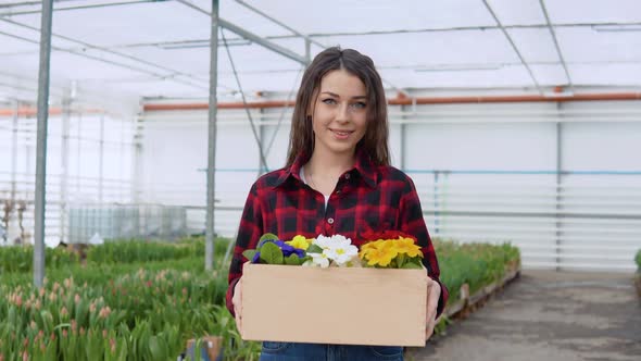 Young Caucasian Girl Florist or Nerd Holding a Craft Box with 5 Pots of Colorful Flowers alt