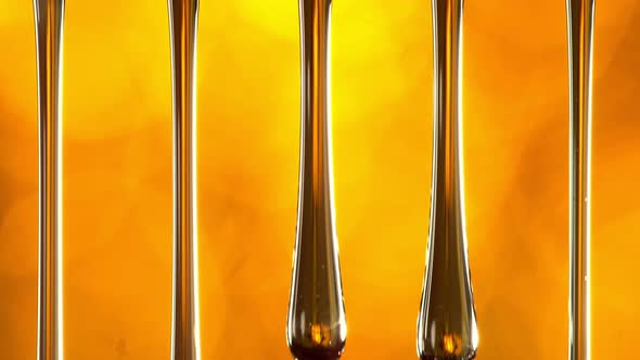 Super Slow Motion Macro Shot of Dripping Oil on Golden Background at 1000 Fps alt