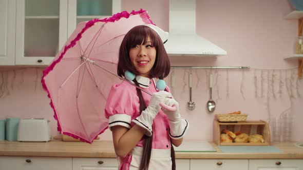 Playful Charming Asian Female in Maid Cosplay Costume Posing with Pink Umbrella alt