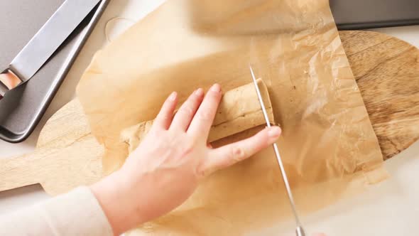 Mother and daughter slicing dough of home made chocolate chip cookies. alt