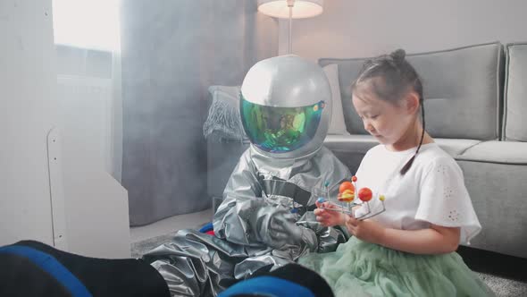Asian Kids Play in the Living Room at Home a Boy in an Astronaut Costume Sitting on the Floor with alt