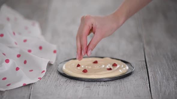 Pastry Chef Hands Sprinkle a Frozen Raspberries on Cake Batter
