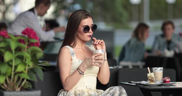 Lovely Girl Drinks Coffee in the Summer Cafe and Waits Her Boyfriend or Best Friend