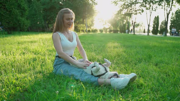 Smiling Woman Petting French Bulldog on Grass.