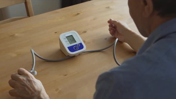 An aged man measuring the blood pressure at home