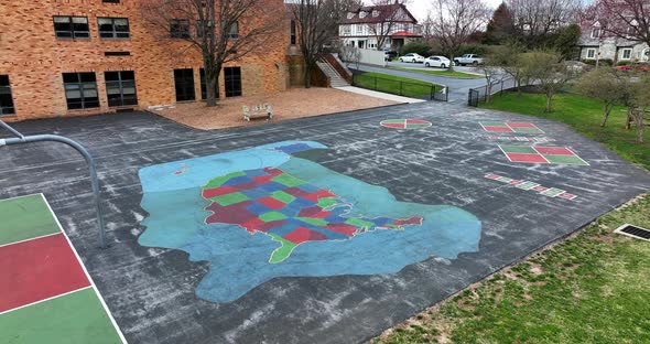 Aerial of school in community. View of playground at recess and approach USA map painted on asphalt alt
