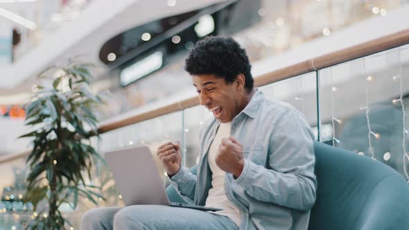 Side View African Guy Male User Online Gambler Plays Betting Game on Internet Receives Cash Prize alt