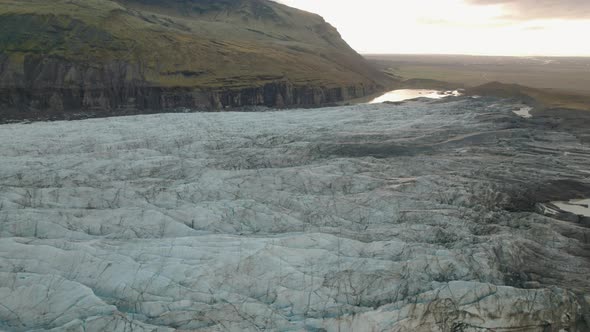 Aerial tilt up over glacier revealing valley and mountains at sunset. Ireland. alt