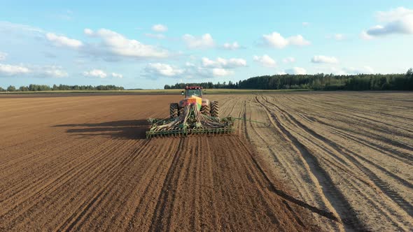 Farmer In Tractor Sows Seeds In Soil Of Agricultural Field On Spring Day Aerial alt