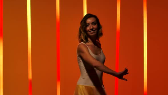 A Professional Ballerina Is Dancing in the Studio Against the Background of Bright Red Orange Neon alt