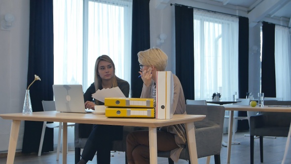 Two female colleagues talking in office