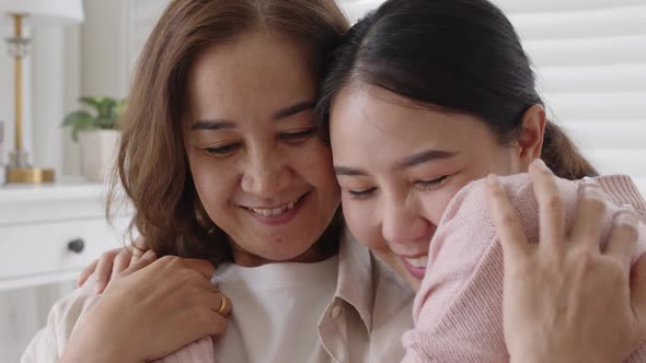 Asian family mother daughter give hug cuddle embrace at home sofa. alt