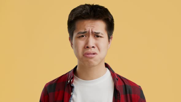 Upset Asian Guy Posing Expressing Sadness Posing Over Orange Background alt