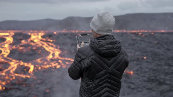 Photographer Controlling Drone And Looking Out Over Lava Field alt
