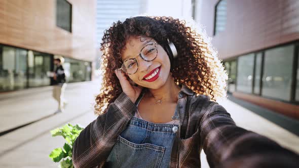 Outdoors Portrait of Cheerful Mixed Race Woman with Curly Hair Chatting and Waving Hand Making Video alt