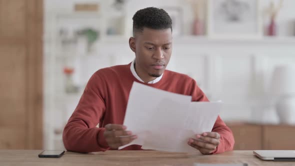 African Man Celebrating Success on Document in Office alt
