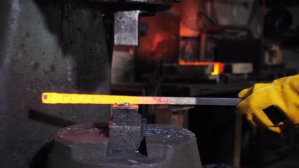 Closeup of a Blacksmith Shifting a Redhot Workpiece Under a Mechanical Hammer