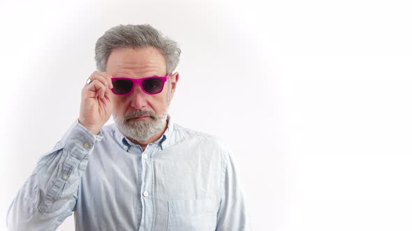 Serious Middle Aged Bearded Greyhaired Man Taking Off Pink Sunglasses White Background Studio Shot alt