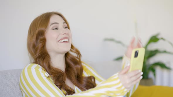 Redheaded woman wondering over video call on smartphone