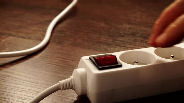Hand Turning On The Power Cord Electrical Extension Block