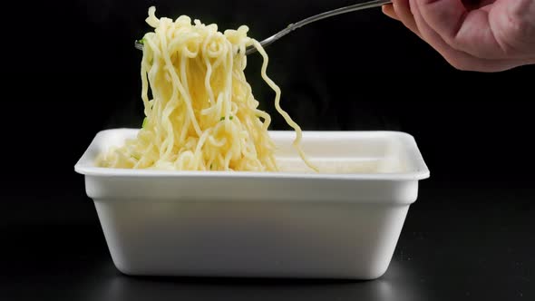 Caucasian Hand with Fork Taking Holding and Putting Back Cooked Instant Noodles From Styrofoam