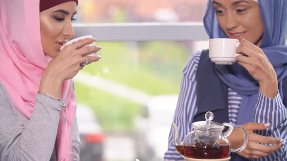 Two Beautiful Young Muslim Women in Cafe Communicate