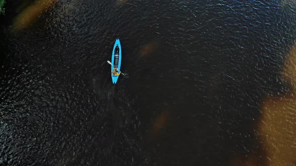 Aerial Flying Above a Wide River with a Man Rowing in a Kayak
