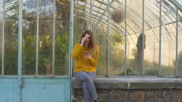 Woman using a smartphone outside of a greenhouse