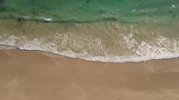Aerial View of Waves Rolling Into Coastline with Person Walking Into Water