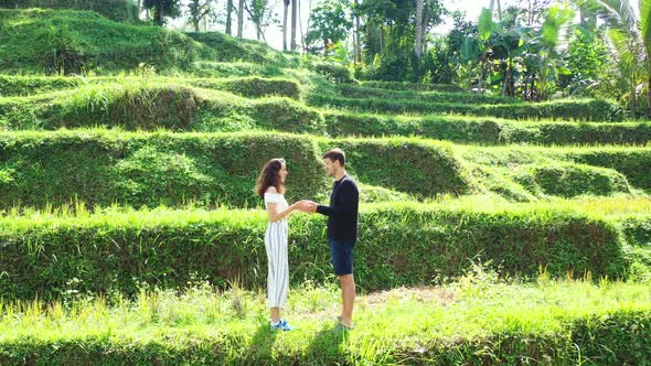Young couple holding hands of each other standing on rice terraces, talking about vacation on exotic alt
