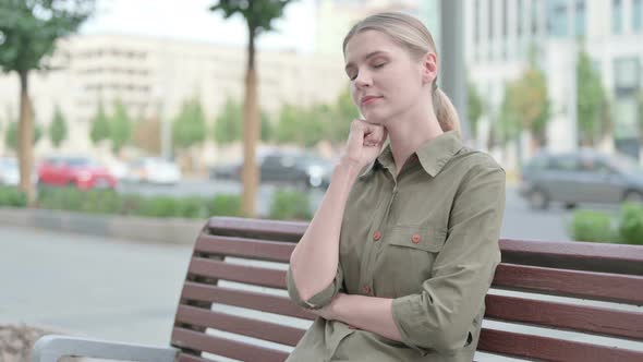 Tired Woman Sleeping while Sitting Outdoor on Bench alt