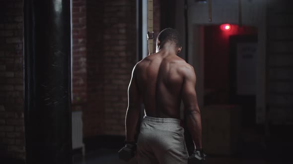 A Black Handsome Man Pumping His Hands Muscles with Dumbbells in the Gym  View of His Back alt