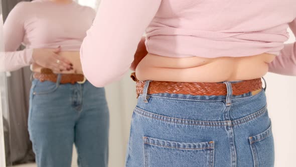 A woman touches her fat body and folds on her sides, fat deposits and excess weight. Body shaming alt