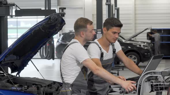 Two Mechanics Doing Computer Diagnostics of a Broken Car