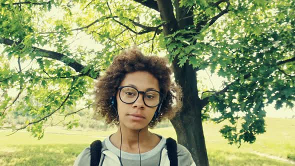 Young African Woman with Headphones Outdoors on Sunny Summer Day alt