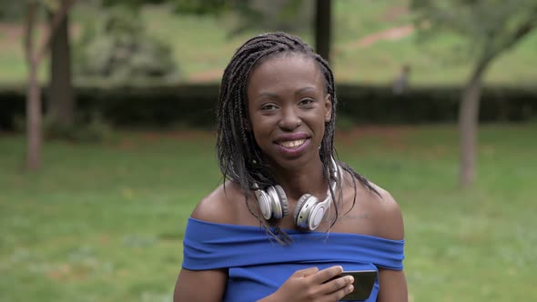 Pretty young black african woman taking selfie and smiling at camera in the park alt