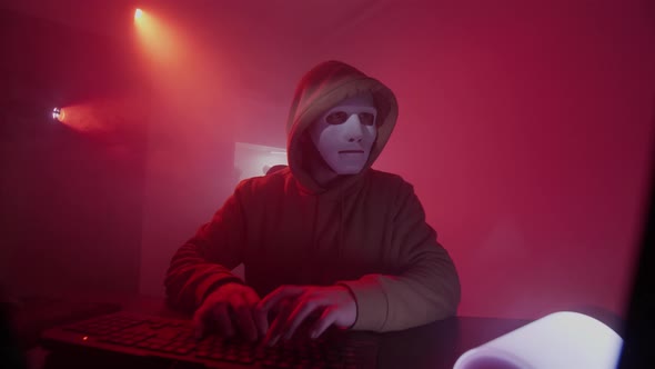 Anonymous Person in a White Mask Works on the Computer Inputs Code Types Very Fast on the Keyboard alt
