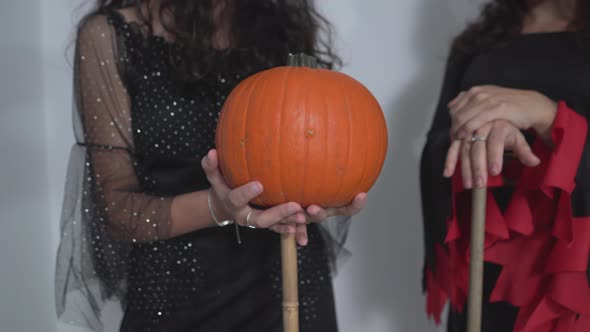 Women In Witch Costume Holding Broomstick And Pumpkin During Halloween alt