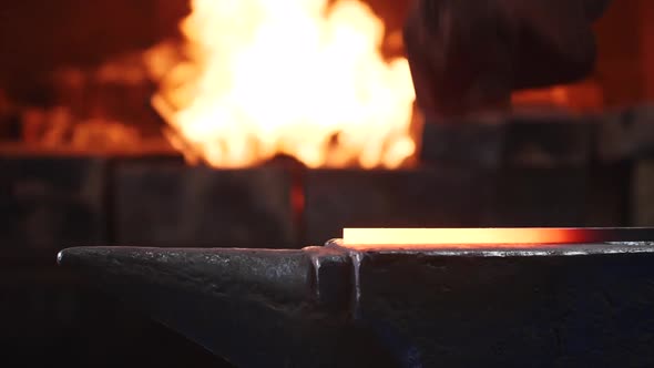 Blacksmith Hitting Hot Metal Bar with Massive Hammer on Anvil in Slow Motion.