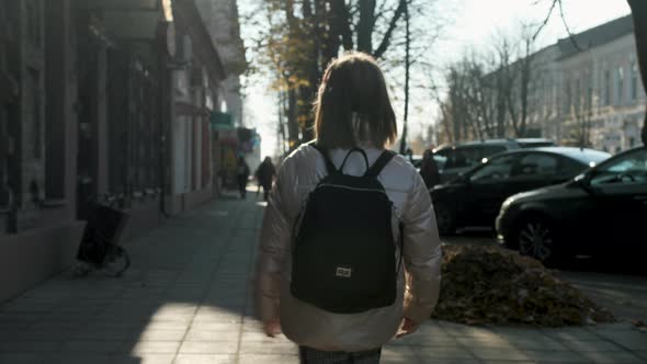 Happy Schoolage Girl with a Backpack Bouncing When Moving alt