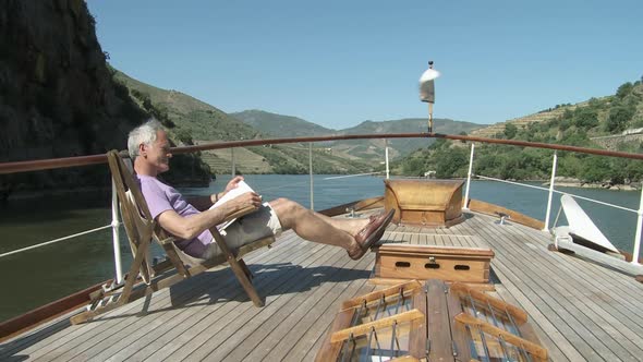 Senior man reading book on a boat alt
