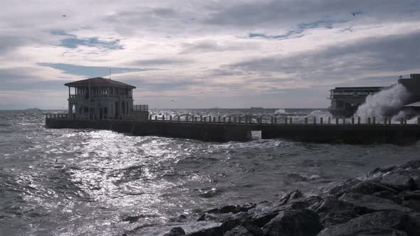 Historical Moda Pier and big splashing waves in stormy day